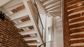 Un escalier avec un mur en briques d’un côté et une rambarde blanche.