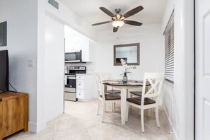 Modern kitchen with white cabinetry, stainless steel appliances, and a potted plant.