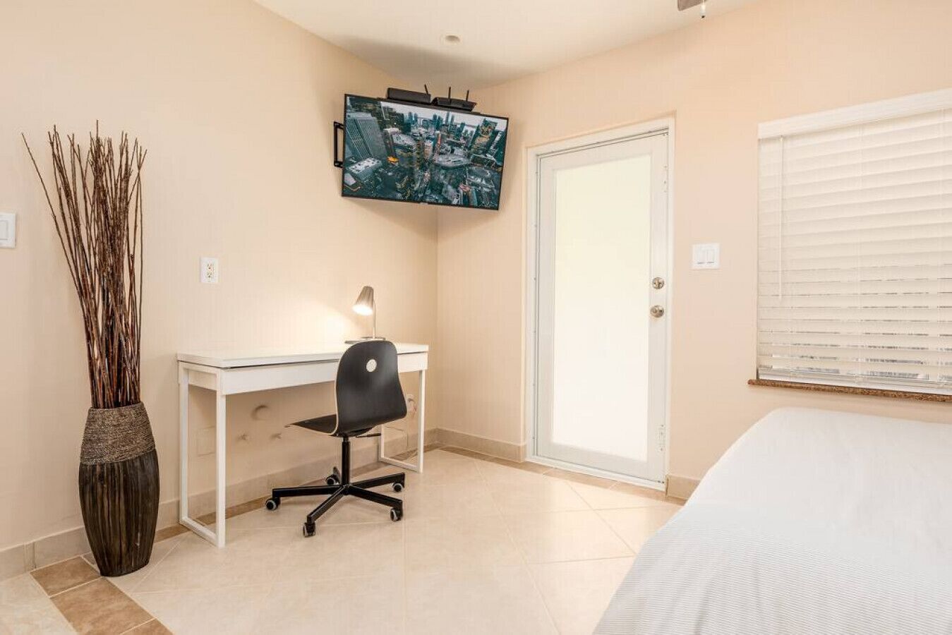 Una camera da letto con un letto, una scrivania, una sedia, una TV e una porta.