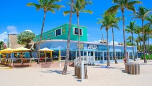 Un restaurant situé en bord de mer, avec une terrasse et des palmiers.