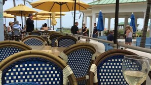 Sitzgelegenheiten im Freien mit Sonnenschirmen, Korbstühle und Meerblick.