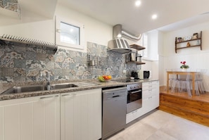 A modern kitchen with white cabinets, a granite countertop, a stainless steel sink, a built-in oven, and a microwave.