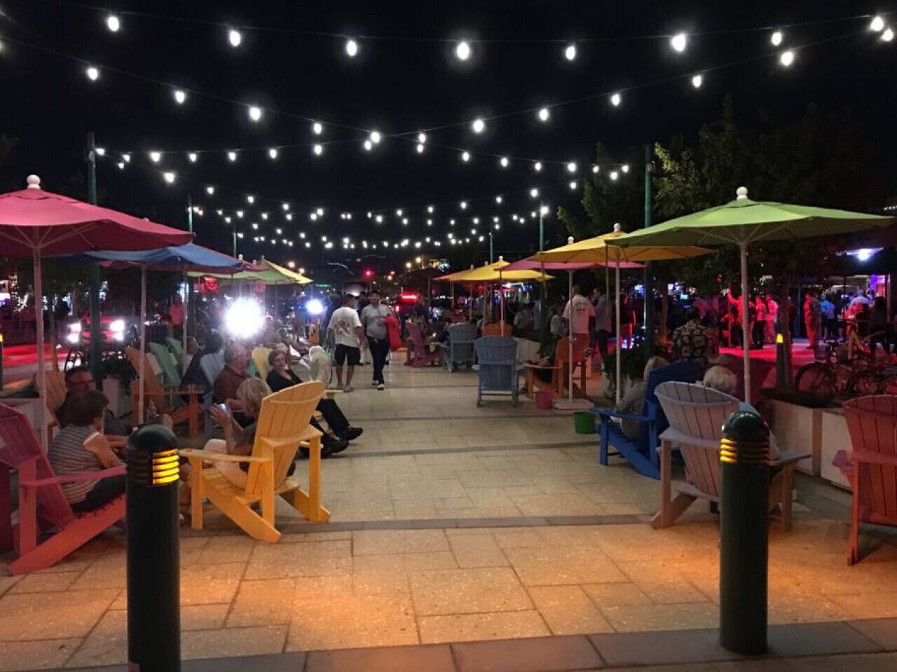 Een marktplein buiten, met lichtjes erboven en verschillende kraampjes.