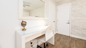 A white desk with a globe and lamp, a mirror above it, and a door with a stone-textured wall.