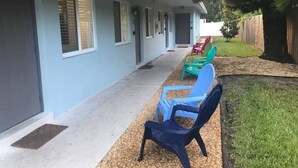 A building with a covered porch, outdoor seating, and a fenced yard.