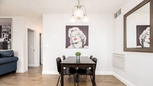 A dining area with a dark wooden table, black chairs, and a small plant on the table. There are two wall-mounted light fixtures above the table. - The Guesthouse #4 - Wilton Manors (Wilton Manors)