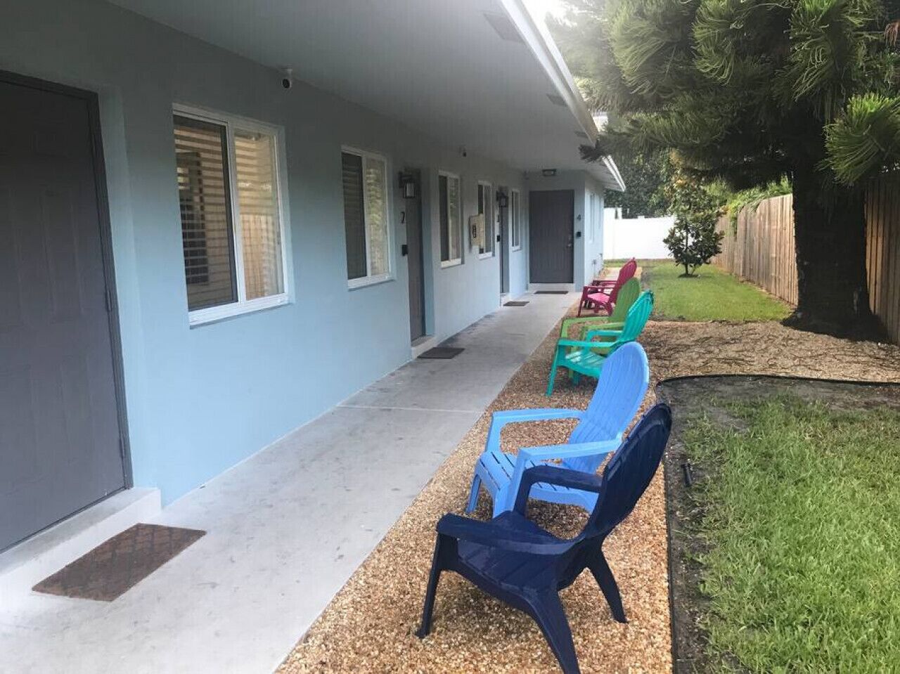 A building with a covered porch, outdoor seating, and a fenced yard.