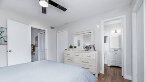 Un dormitorio con cama, cómoda, espejo y ventilador de techo.