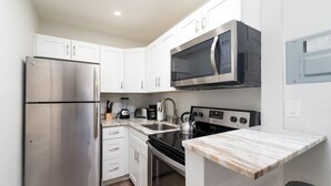 A compact kitchen with stainless steel appliances, a microwave, a kettle, and a built-in oven. - The Hideaway at Lake Ridge #2 (Fort Lauderdale)