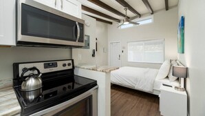 A compact kitchen with a microwave, stove, kettle, and a small dining area. - The Hideaway at Lake Ridge #2 (Fort Lauderdale)