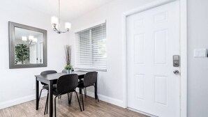 Un espace repas comprenant une table et des chaises, un lustre, un miroir et une porte.