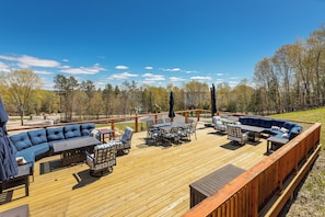 A deck with outdoor furniture, including a sofa, chairs, and a table. - Luxury Torch Lake Vacation Home – Private Dock, Pickleball, Game Room, Theatre (Kewadin)