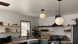 A modern kitchen with a central island, black appliances, and pendant lighting. - Convenient Getaway in the Heart of Hudson Valley (Tillson)