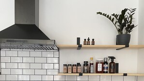 A modern kitchen with a stainless steel range hood, a Samsung digital clock, and a variety of spices and oils on wooden shelves. - Convenient Getaway in the Heart of Hudson Valley (Tillson)