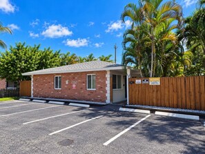 A small brick building with a garage, a wooden fence, and a parking lot. - The Palms @ Middle River Terrace #2 (Fort Lauderdale)