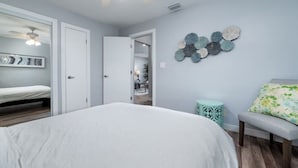 A bedroom with a bed, a ceiling fan, a wall with decorative plates, and a bench.