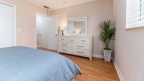 Quarto com cama, penteadeira, espelho e planta em vaso.