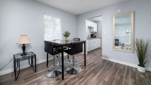 A modern kitchen with white cabinets, a wooden countertop, and a dining area with a table and chairs.