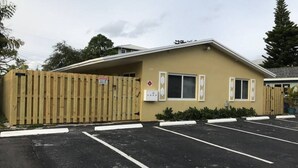 Un edificio con facciata color beige, un ingresso protetto da cancello e un parcheggio con posti delimitati.