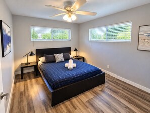 A bedroom with a bed, two bedside tables, a ceiling fan, and two windows with blinds. - The Palms @ Middle River Terrace #4 (Fort Lauderdale)