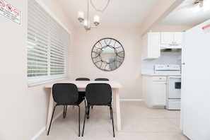 Functional kitchen with oven, dining table for four, and decorative mirror.
