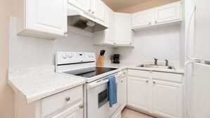 A modern kitchen with white cabinetry, a stove, oven, and a sink. - The Retreat #1 - Wilton Manors (Wilton Manors)