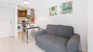 Un appartement moderne avec un canapé gris, une table à manger et un coin cuisine.