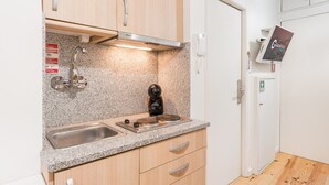 Une cuisine de taille réduite dotée de plans de travail en granit, d’appareils électroménagers en acier inoxydable et d’armoires en bois.