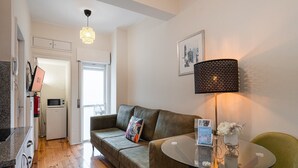 A modern living room with a sofa, a glass coffee table, a lamp, and a framed picture on the wall.
