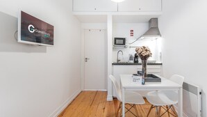 A compact kitchen with a microwave, a coffee maker, and a vase with dried flowers on the counter. - GuestReady Economy - Riber Porto 4R (Porto)