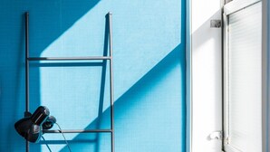 A room with a blue wall, a metal ladder, and a window with a white frame. - GuestReady Economy - Riber Porto 4R (Porto)
