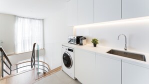 A modern kitchen with a built-in washer and dryer, a stainless steel sink, and a small potted plant. - GuestReady - Porto by the Bridge (Vila Nova de Gaia)