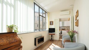 Een moderne woonkamer met een houten kast, een televisie en een zithoek met een tafel en stoelen.