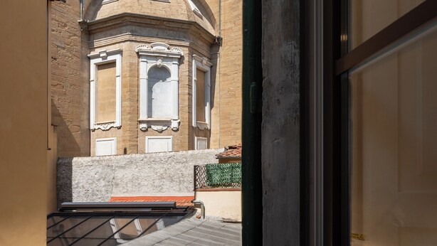 Ein Innenhof mit einem Gebäude, das gewölbte Fenster und ein Ziegeldach aufweist.