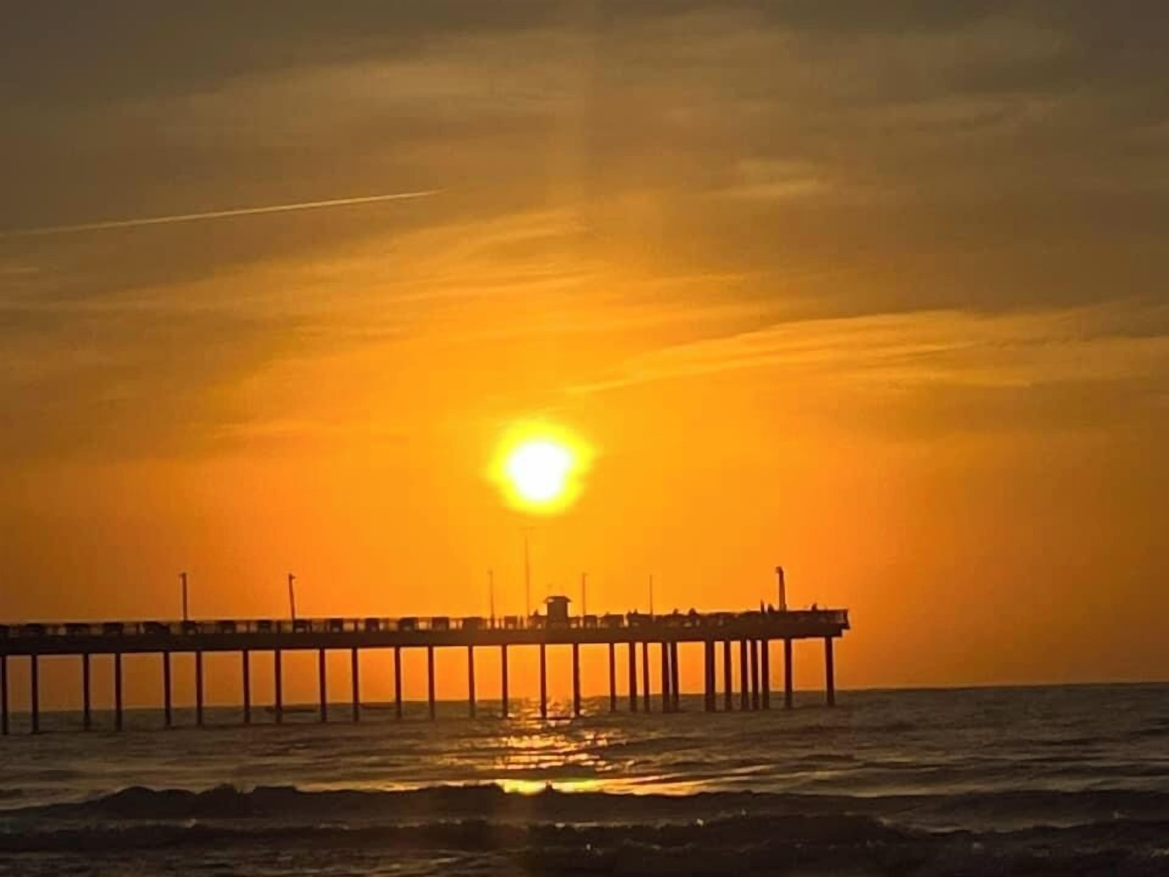 A pier extending into the sea during sunset.
