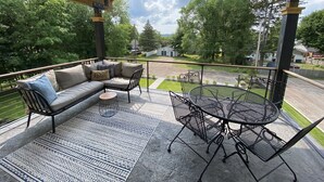A covered patio with a sofa, chairs, and a table. - The Sunset View Penthouse Loft (Boyne City)