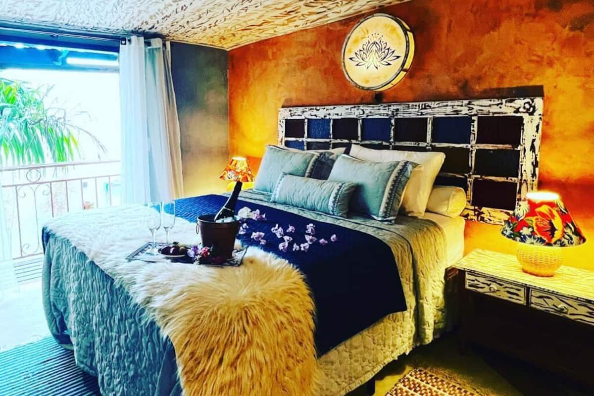 A bedroom with a bed, a nightstand, a lamp, and a decorative wall piece.