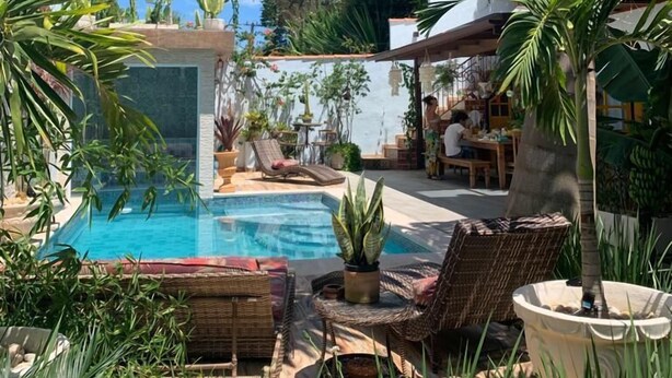 A pool area with lounge chairs, a dining area, and a view of the ocean. - Villa Lulu Buzios (Búzios)