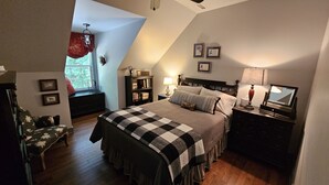 A bedroom with a large bed, a nightstand, a dresser, a window with curtains, a bookshelf, and framed pictures on the wall. -  Loft apartment in a working horse barn.  Minutes from Lexington and the  VAHC. (Lexington)