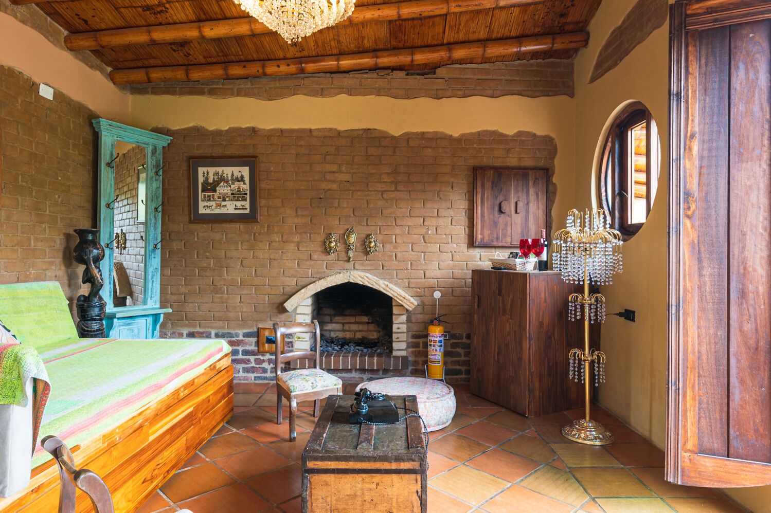 Una habitación rústica con chimenea de ladrillo, muebles de madera y un candelabro.