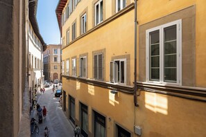 Une rue étroite bordée de bâtiments des deux côtés, où se côtoient différents styles architecturaux, et où le ciel est dégagé.