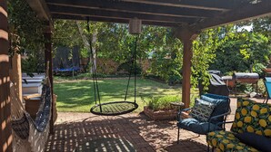 Una veranda riparata con un'amaca, un barbecue e una sedia a dondolo.
