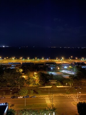 A nighttime aerial view of a cityscape with illuminated roads, a bridge, and surrounding greenery. - 25homeapart (Encarnacion)
