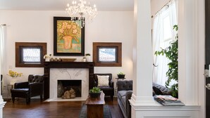 A living room with a fireplace, two armchairs, a sofa, a coffee table, and a chandelier. - Room for Everyone! 7BR, 6.5BA Wine Country Retreat near Downtown (McMinnville)