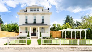 A two-story house with a front porch, a wooden fence, and a pergola. - Room for Everyone! 7BR, 6.5BA Wine Country Retreat near Downtown (McMinnville)