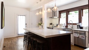 A modern kitchen with a large island, bar stools, stainless steel appliances, and pendant lighting. - Room for Everyone! 7BR, 6.5BA Wine Country Retreat near Downtown (McMinnville)