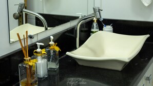 A bathroom with a white sink, black countertop, and a mirror above the sink. - Hostel Santa Rita (Santa Rita De Cassia)