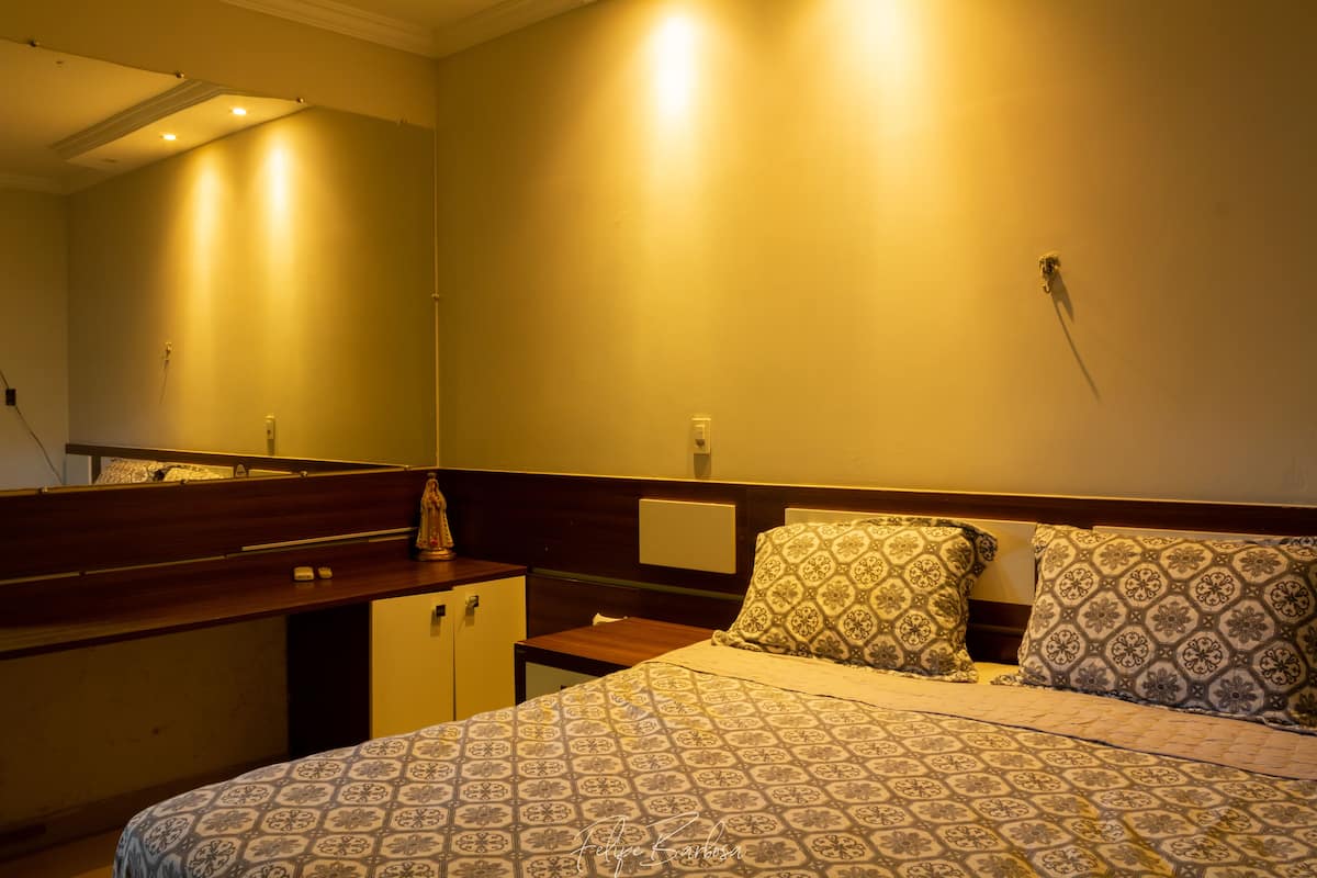 A bedroom with a bed, a nightstand, a dresser, and a mirror.