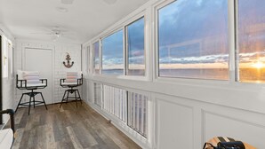 Ein Zimmer mit großen Fenstern, einem Deckenventilator und Blick auf den Sonnenuntergang.