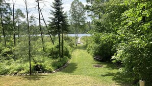 A pathway leading to a bench and a small pond surrounded by dense greenery and trees.